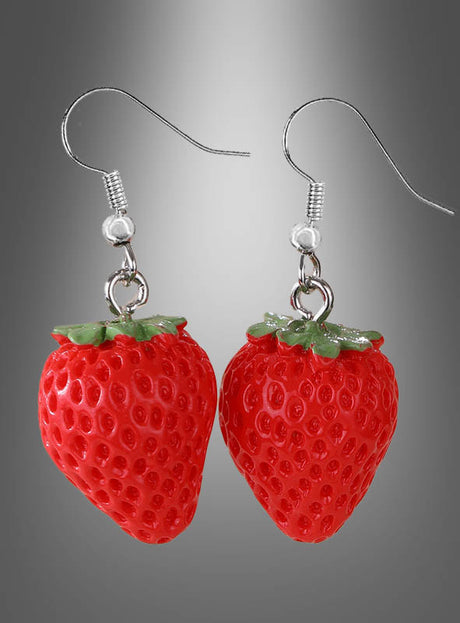 Ein Paar „Erbeeren“-Ohrringe – als Anhänger oder Stecker in Form von Erdbeeren mit grünen Blättern, die an silberfarbenen Haken hängen – präsentiert vor einem grauen Hintergrund mit Farbverlauf – ein verspieltes Stück Sommer-Modeschmuck, das sich perfekt für jede Fruchtschmuck-Kollektion eignet.