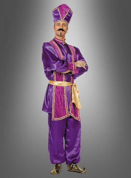 Ein Mann, der das farbenfrohe „Orientalischer Sultan“-Kostüm trägt – ein auffälliges Outfit in Lila und Gold mit einem passenden hohen Hut, goldenen Schuhen und einem Schnurrbart –, steht mit verschränkten Armen vor einem grauen Hintergrund.