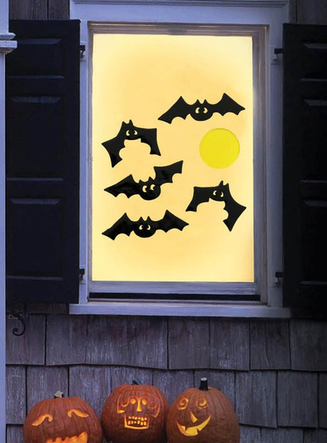 In einem Fenster sind Papierfledermäuse und ein gelber Kreis zu sehen, die durch drei geschnitzte Kürbisse auf der Fensterbank draußen ergänzt werden. Die festliche Kulisse wird durch das Halloween-Fenster-Deko-Set aus Gel (20 x 19 cm) abgerundet, dessen wiederverwendbare Gel-Fensteraufkleber dem Ganzen eine verspielte Note verleihen, während sie am Glas haften.
