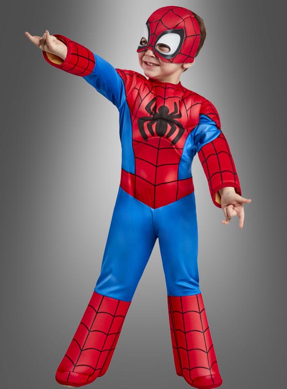 Ein Kind, das ein Spidey-Spiderman-Kostüm für kleine Kinder und eine Maske trägt, posiert mit einem nach vorne ausgestreckten Arm vor einem einfarbigen Hintergrund.