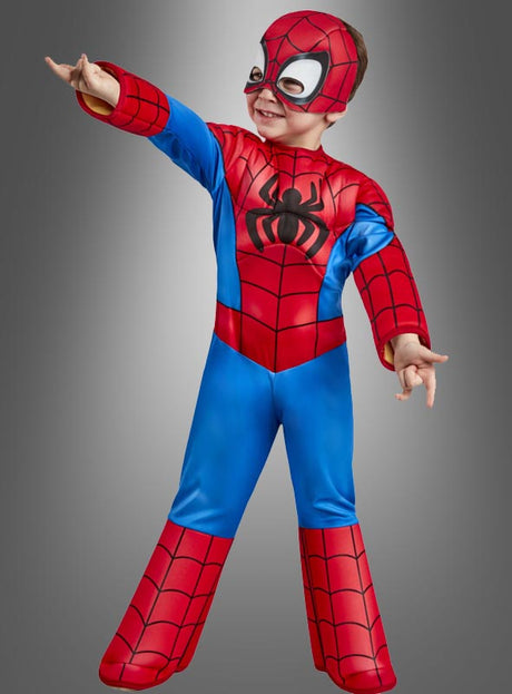 Ein Kind, das ein Spidey-Spiderman-Kostüm für kleine Kinder und eine Maske trägt, posiert mit einem nach vorne ausgestreckten Arm vor einem einfarbigen Hintergrund.