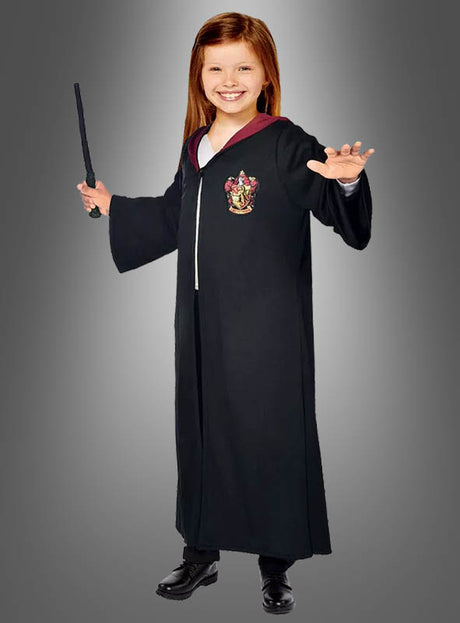 Ein Kind, das den Hermine-Granger-Gryffindor-Umhang aus „Harry Potter“ trägt, in der einen Hand einen Zauberstab hält und die andere Hand hebt, steht vor einem grauen Hintergrund mit Farbverlauf.