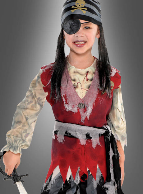 Ein Kind in einem „Toter Pirat“-Kinderkostüm – mit gestreiftem Bandana, Augenklappe, roter, zerrissener Weste und einem Spielzeugschwert in der Hand – steht vor einem grauen Hintergrund.