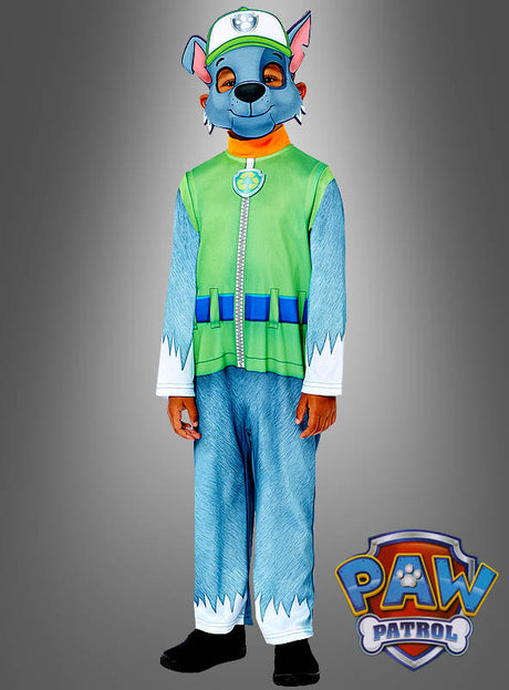 Ein Kind im Rocky-Kostüm aus „Paw Patrol“, bestehend aus einem grünen Oberteil, einer blauen Hose und einer Rocky-Maske, steht vor einem grauen Hintergrund, auf dem in der Ecke das „PAW Patrol“-Logo zu sehen ist.