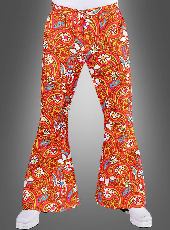 Eine Person trägt die „Bunte Schlaghose Martin für Herren“ in leuchtendem Orange mit einem auffälligen Paisley- und Blumenmuster, das an ein Kostüm aus den 70er Jahren erinnert, und steht vor einem grauen Hintergrund.