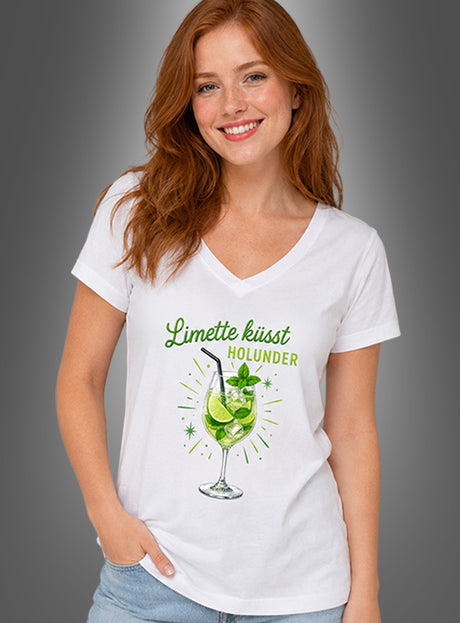 Eine Frau mit langen roten Haaren trägt das Cocktail-T-Shirt „Limette küsst Holunder“, ein weißes Damen-Sommer-T-Shirt mit V-Ausschnitt, das auf grauem Hintergrund mit einem Cocktail-Motiv und dem Schriftzug „Limette küsst Holunder“ verziert ist.