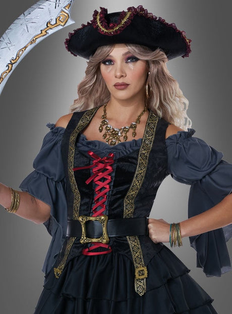 Eine Frau im „Königin der Weltmeere“-Piratenkostüm aus schwarzem und grauem Stoff mit roten Schnürungen und einem passenden Piratenhut posiert mit einem großen Schwert vor einem schlichten grauen Hintergrund.
