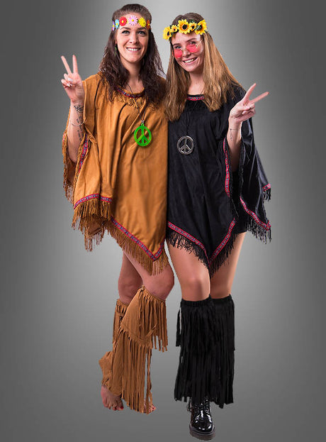 Zwei Frauen in Hippie-Outfits mit Fransen, Blumenkränzen und Halsketten mit Peace-Zeichen tragen jeweils bunte Hippie-Stulpen mit Fransen. Lächelnd und mit erhobenen Peace-Zeichen stehen sie vor einem schlichten grauen Hintergrund.