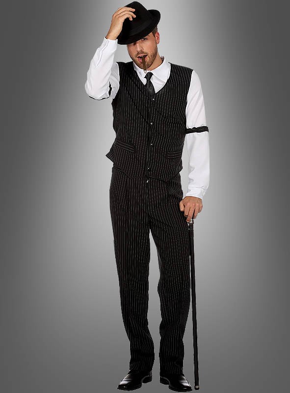Ein Mann im „Lässigen Mafia-Outfit für Herren“ – einem schwarzen Nadelstreifenanzug, einem weißen Hemd, einer schwarzen Krawatte und einem Hut – hält einen Spazierstock in der Hand und tippt an seinen Hut, während er vor einem grauen Hintergrund steht und dabei den unverkennbaren Gangster-Look der 20er Jahre à la Al Capone verkörpert.