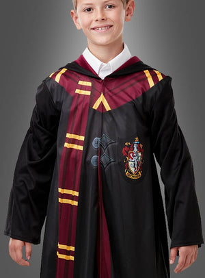 Ein lächelndes Kind im Harry-Potter-Kostüm mit Gryffindor-Aufdruck: eine schwarze Robe mit kastanienbraunen und goldenen Streifen sowie einem Wappen – perfekt für jeden jungen Harry-Potter-Fan, der sich einen authentischen Hogwarts-Look wünscht.