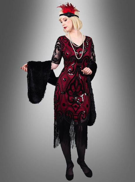 Eine Person, die das „Halbarm 20er Jahre Retro Kleid Francis“ trägt – ein Kleid im Stil der 1920er Jahre, verziert mit schimmernden Details, die an ein klassisches Paillettenkleid erinnern –, ergänzt durch eine lange Perlenkette, ein Stirnband mit einer roten Feder, einen schwarzen Schal und schwarze Schuhe, vor einem grauen Hintergrund mit Farbverlauf.