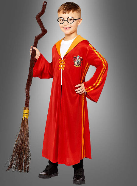 Ein Kind, das die „Rote Quidditch-Robe aus Harry Potter“ trägt – komplett mit gelben Streifen, runder Brille und einem Besen –, steht vor einem schlichten grauen Hintergrund.