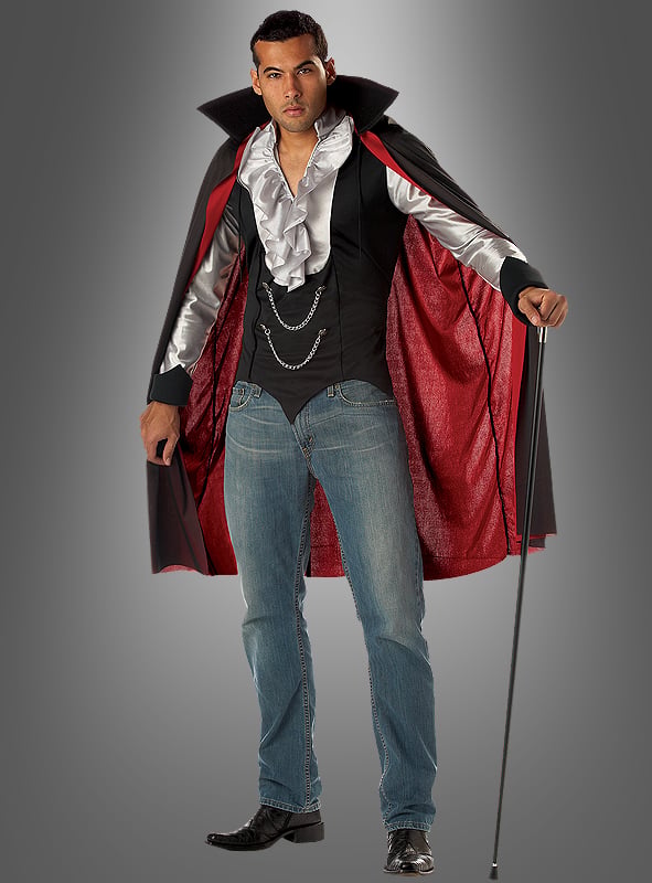 Ein Mann, der das „Cooler Vampir“-Halloweenkostüm trägt – bestehend aus einem schwarz-roten Umhang mit Kragen, einem Rüschenhemd, Jeans und schwarzen Schuhen –, steht vor einem grauen Hintergrund und hält einen Spazierstock in der Hand.
