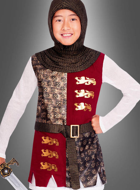 Ein Kind im Kinderkostüm „Mittelalterlicher Ritter Galahad mit Schwert“, bestehend aus einer Kapuze im Kettenhemd-Look, einer mit Löwenwappen verzierten Tunika und einem dazu passenden Spielzeugschwert, steht stolz vor einem grauen Hintergrund – ganz im Stil des legendären Sir Galahad.