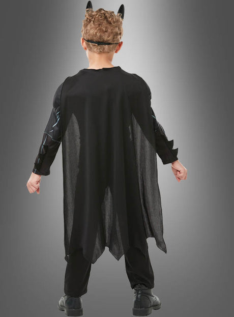 Ein Kind, das das Batman-Kinderkostüm mit Maske trägt – bestehend aus einem schwarzen Superheldenumhang und einem Stirnband mit spitzen Ohren –, steht mit dem Rücken zur Kamera vor einem grauen Hintergrund mit Farbverlauf – ideal für Fans aller DC-Comics-Lizenzkostüme.