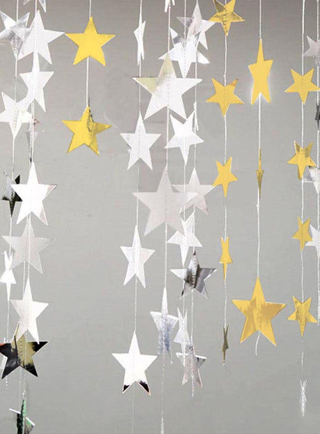 Gold- und silberfarbene „Sternengirlande“-Partydeko (360–400 cm) hängt an Schnüren vor einem schlichten grauen Hintergrund und sorgt so für eine festliche Dekoration, die sich perfekt für jede Party im Hollywood-Stil eignet.