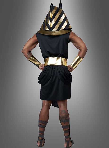 Eine Person in einem „Ägyptischer Gott Anubis Deluxe“-Kostüm steht mit dem Rücken zur Kamera und trägt einen gestreiften Kopfschmuck, der vom Gott der Toten inspiriert ist, einen breiten goldenen Gürtel, goldene Armreifen und schwarze Sandalen.
