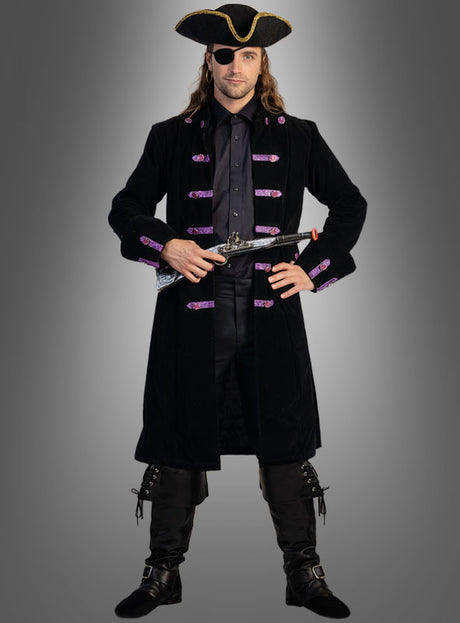 Eine als Pirat verkleidete Person steht mit dem Gesicht nach vorne und trägt den „Piraten Mantel Jackson Herren“ – einen schwarzen Mantel mit violetten Besätzen – sowie schwarze Stiefel, einen Dreispitz, eine Augenklappe und hält eine Pistole in der Hand.