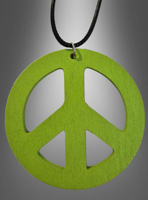 Eine 70er-Jahre-Friedenskette aus Holz (6,50 cm) mit einem grünen Holzanhänger in Form eines Peace-Zeichens hängt an einer schwarzen Kordel vor einem grauen Hintergrund mit Farbverlauf – perfekt als Peace-Zeichen-Kette oder Holzamulett für dein nächstes Hippie-Kostüm.