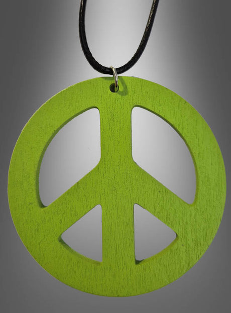 Eine 70er-Jahre-Friedenskette aus Holz (6,50 cm) mit einem grünen Holzanhänger in Form eines Peace-Zeichens hängt an einer schwarzen Kordel vor einem grauen Hintergrund mit Farbverlauf – perfekt als Peace-Zeichen-Kette oder Holzamulett für dein nächstes Hippie-Kostüm.