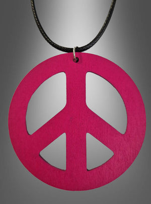 Eine 70er-Jahre-Friedenskette (6,50 cm) aus Holz in Rosa, ideal als Holzamulett für dein Hippie-Kostüm, hängt an einer schwarzen Kordel vor einem grauen Farbverlaufshintergrund.