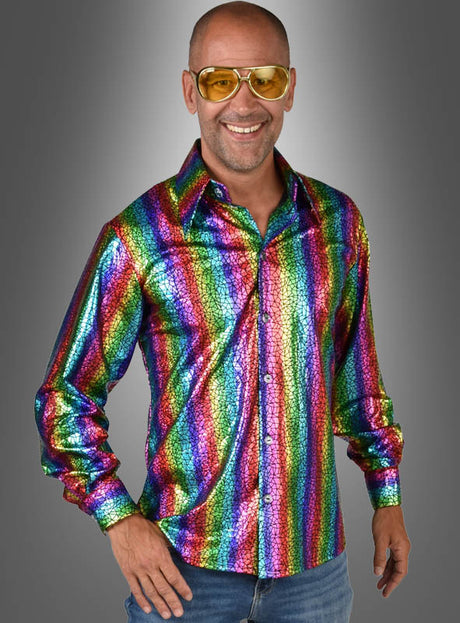 Ein lächelnder Mann mit gelber Sonnenbrille und einem glänzenden „Hologramm Party Hemd Regenbogen“, der vor einem grauen Hintergrund mit Farbverlauf steht.