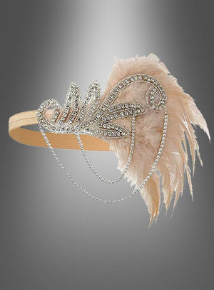 Der Kopfschmuck „20er Jahre mit Strass Alice“ ist ein beiges Haarband, das mit Strasssteinen und Perlen verziert ist und zarte, blassrosa Federn sowie herabhängende Perlenstränge aufweist. Es erinnert an den Glamour des Vintage-Kopfschmucks der 20er Jahre und lässt sich mühelos mit jedem Charleston-Kleid kombinieren. Vor einem grau verlaufenden Hintergrund präsentiert, verkörpert dieses elegante Haarband die Essenz zeitloser Raffinesse.
