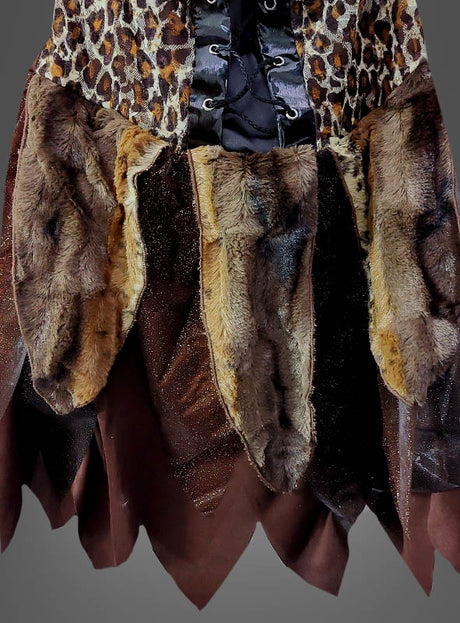 Eine Nahaufnahme des Steinzeit-Kostüms „Leo Look“ zeigt braune und hellbraune Kunstfell-Einsätze, Stoff mit Tiermuster, der an ein Leopardenkleid erinnert, ein schwarzes Satinband sowie gezackte braune Stoffkanten.