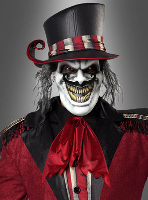 Eine Person, die das „Wandelbares Zirkusdirektor-Kostüm für Herren“ trägt – ein unheimliches Clown-Outfit mit einem hohen gestreiften Hut, weißer Gesichtsbemalung, einem übertriebenen schwarzen Grinsen mit gelben Zähnen sowie einem rot-schwarzen Outfit, das von einer großen roten Schleife gekrönt wird – ideal, um als Halloween-Kostüm für Herren ein kühnes Statement zu setzen oder Ihrem Zirkusdirektor-Kostüm eine düstere Note zu verleihen.