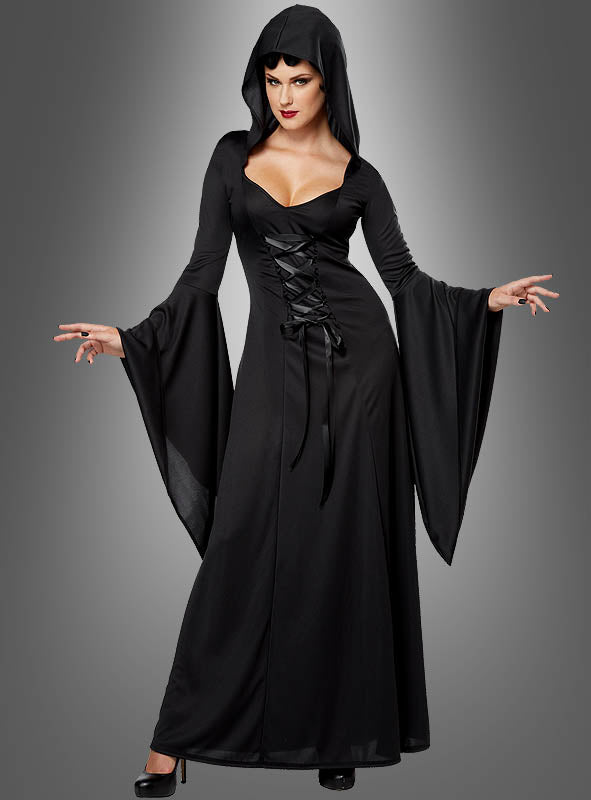 Vor einem grauen Hintergrund mit Farbverlauf steht eine Frau, die im „Kapuzenkleid Carmilla“ – einem langen, schwarzen Kleid im Gothic-Stil mit ausgestelltem Ärmeln und Schnürung vorne – geheimnisvolle Eleganz verkörpert und damit die perfekte Wahl für ein bezauberndes Halloween-Kostüm darstellt.