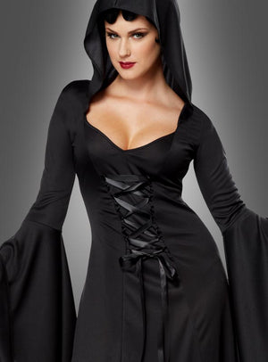 Eine Frau im Kapuzenkleid „Carmilla“ – ein schwarzes, langärmeliges Gothic-Kleid mit Schnürung und Kapuze – steht vor einem grauen Hintergrund mit Farbverlauf.