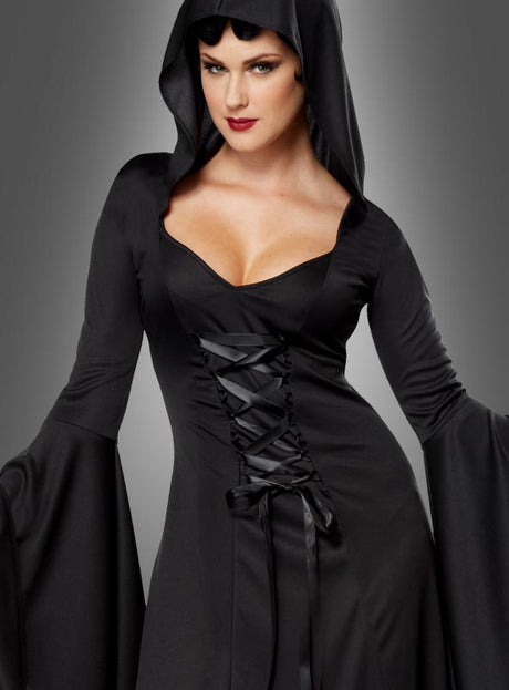 Eine Frau im Kapuzenkleid „Carmilla“ – ein schwarzes, langärmeliges Gothic-Kleid mit Schnürung und Kapuze – steht vor einem grauen Hintergrund mit Farbverlauf.