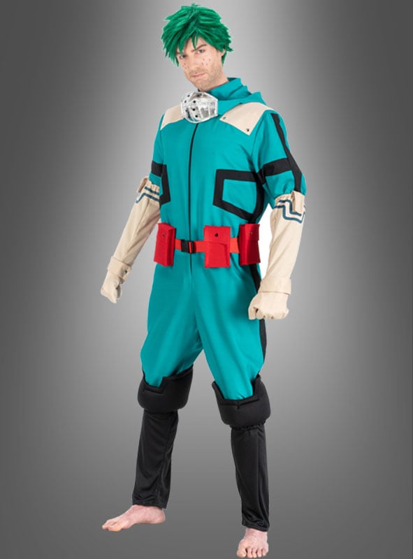 Eine Person, die das Izuku-Midoriya-Kostüm für Erwachsene aus „My Hero Academia“ trägt – ein blaugrünes und beiges Superheldenkostüm mit roten Aufstecktaschen –, steht barfuß vor einem grauen Hintergrund mit Farbverlauf.