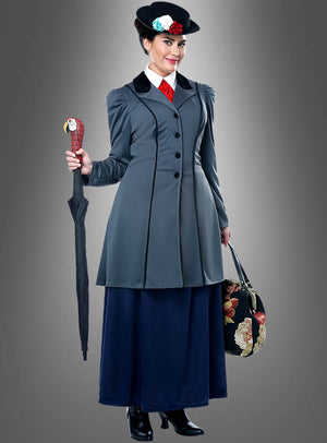 Eine Frau im „Nanny-Kostüm für Damen“ – einem von Mary Poppins inspirierten grauen Mantel im Vintage-Stil, einem mit Blumen verzierten schwarzen Hut, einem Regenschirm mit Papageiengriff und einer mit Blumen verzierten Reisetasche – steht vor einem schlichten grauen Hintergrund.