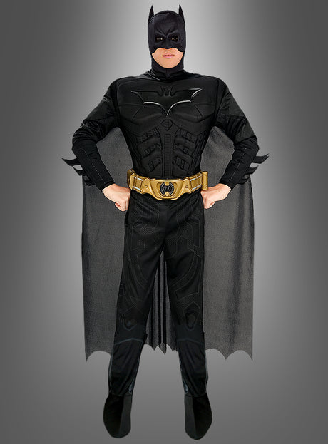 Eine Person, die das „Batman: The Dark Knight“-Kinofilm-Kostüm trägt – ein offizielles Batman-Lizenzprodukt, bestehend aus einem schwarzen Superhelden-Outfit mit Umhang und goldenem Werkzeuggürtel –, steht selbstbewusst mit den Händen in den Hüften vor einem grauen Hintergrund. Dieses Kostüm ist ideal für Fans, die ein authentisches „Batman: The Dark Knight“-Kostüm oder ein auffälliges Batman-Kostüm für Erwachsene suchen.