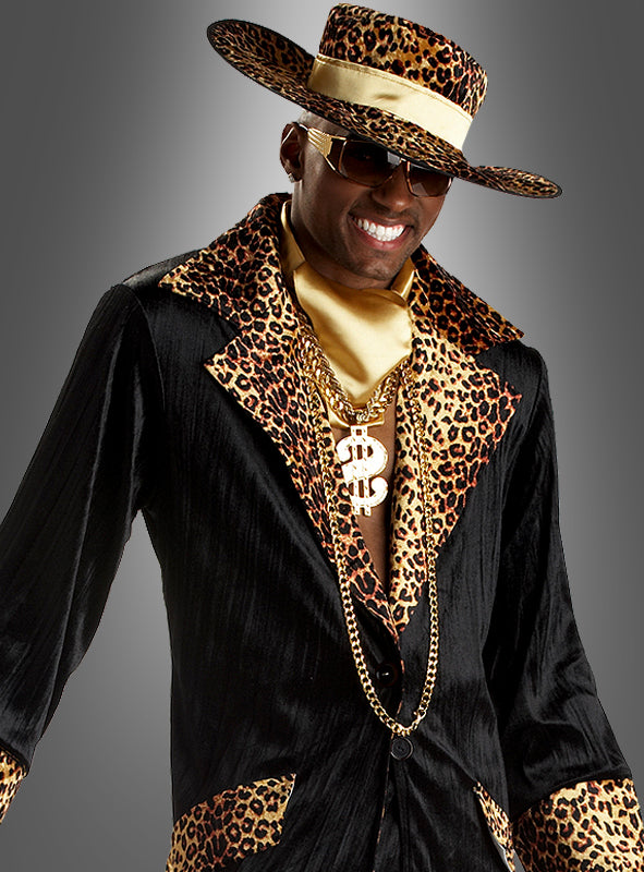 Das 70er-Jahre-Pimp-Kostüm „Mac Daddy“ – bestehend aus einem schwarzen Anzug mit Leopardenmuster-Besatz, einem passenden Hut mit breiter Krempe, einer goldenen Sonnenbrille sowie goldenen Ketten mit einer auffälligen Halskette mit Dollarzeichen – sorgt vor einem grauen Hintergrund für einen kultigen Look, perfekt für jede 70er-Jahre-Kostümparty oder als ultimatives Mac-Daddy-Statement.