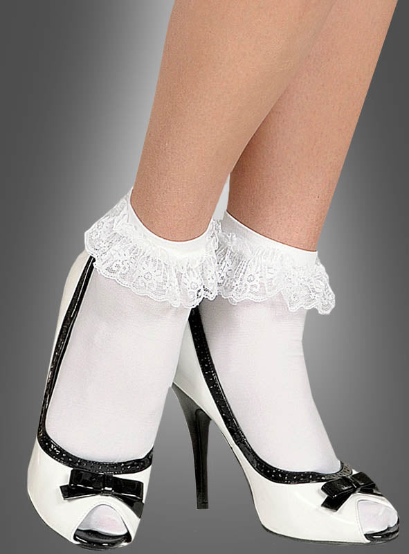 Eine Person, die weiße Socken mit Spitze und schwarz-weiße Schuhe mit hohen Absätzen und Schleifen trägt und vor einem grauen Hintergrund steht, vermittelt den Eindruck eines verspielten Rock’n’Roll-Kostüms.