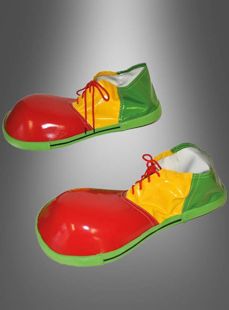 Ein Paar übergroße, farbenfrohe Clown-Schuhe für Erwachsene mit roten Zehen, gelbem Mittelfuß, grünen Absätzen und Sohlen sowie roten Schnürsenkeln vor einem grauen Hintergrund mit Farbverlauf – der perfekte letzte Schliff für jedes Clownskostüm.