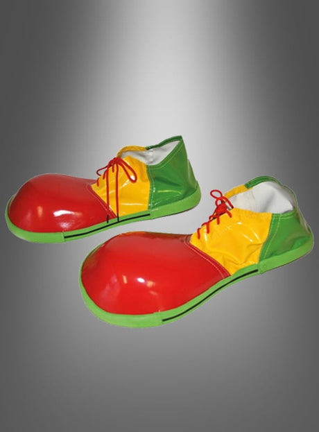 Ein Paar Clownschuhe für Erwachsene, im Oversize-Stil, mit leuchtend roten Vorderkappen, gelben Seiten, grünen Absätzen und Sohlen sowie knallroten Schnürsenkeln, präsentiert vor einem grau verlaufenden Hintergrund – perfekt, um jedes Clownskostüm abzurunden.