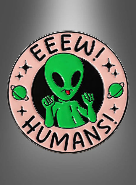 Ein runder Anstecker mit dem Namen „Alien Pins Anstecker Weltall“ zeigt einen grünen Cartoon-Außerirdischen mit erhobenen Händen, umgeben von dem Schriftzug „EEEW! MENSCHEN!“ auf einem rosa Rand, der mit kleinen Planeten und Sternen verziert ist – damit ist er die ideale Wahl für Fans von Alien Pins oder alle, die lustige Anstecker lieben.