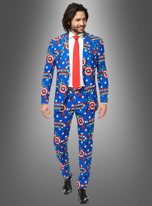 Ein Mann in einem blauen „Deluxe Captain America OppoSuit“-Anzug mit den ikonischen Schilden, einer roten Krawatte, einem weißen Hemd und schwarzen Schuhen steht vor einem grauen Hintergrund mit Farbverlauf.