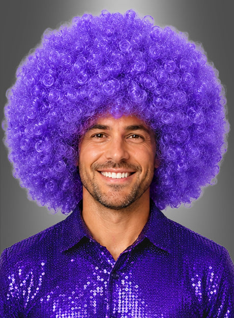 Ein Mann lächelt, während er eine riesige Afro-Perücke in XXL trägt – groß und lockig in leuchtendem Lila –, dazu ein glänzendes lila Paillettenhemd, vor einem schlichten grauen Hintergrund.