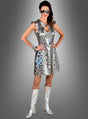 Eine Frau in einem 70er-Jahre-Disco-Kleid mit silbernen Hologrammkreisen steht selbstbewusst mit den Händen in den Hüften da, trägt eine Sonnenbrille und Armbänder und steht vor einem grauen Hintergrund mit Farbverlauf.