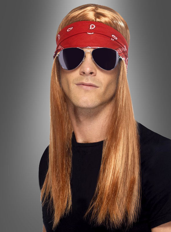Mit der Perücke aus dem „90er-Jahre-Rockstar-Set“ und der Brille – langes, glattes, rötlich-blondes Haar, rotes Bandana, dunkle Sonnenbrille und ein schwarzes T-Shirt – ist dieser klassische Look ideal für jede 90er-Jahre-Party oder jedes Rockstar-Motto vor einem grauen Hintergrund.