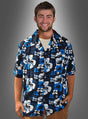 Ein Mann steht lächelnd vor einem grauen Hintergrund mit Farbverlauf und trägt das Hawaii-Hemd „Blütenmeer blau“ mit blauen, weißen und schwarzen Blumenmustern sowie eine hellbraune Hose – die perfekte Kleidung für jede Strandparty.