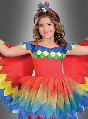 Ein Kind posiert mit ausgestreckten Armen vor einem grauen Hintergrund. Es trägt das farbenfrohe „Paradiesvogel-Papagei-Kostüm für Mädchen“ mit gefiederten Flügeln, einem bunten Tutu und einem passenden Stirnband – die ideale Wahl für den Kinderfasching als auffälliges Paradiesvogel-Kostüm.