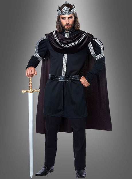 Vor einem grauen Hintergrund steht ein Mann, der eine silberne Krone, einen schwarzen Umhang und das mittelalterliche Kostüm „König Kostüm schwarz für Herren“ trägt und ein nach unten gerichtetes Schwert in der Hand hält.