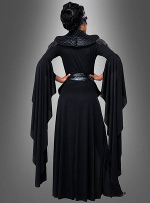 Eine Person, die das Kostüm der „Schwarzen Königin der Toten“ trägt – bestehend aus einem langen schwarzen Kleid mit dramatisch fließenden Ärmeln –, steht mit dem Rücken zu einem grauen Hintergrund mit Farbverlauf und strahlt dabei eine geheimnisvolle Eleganz aus.