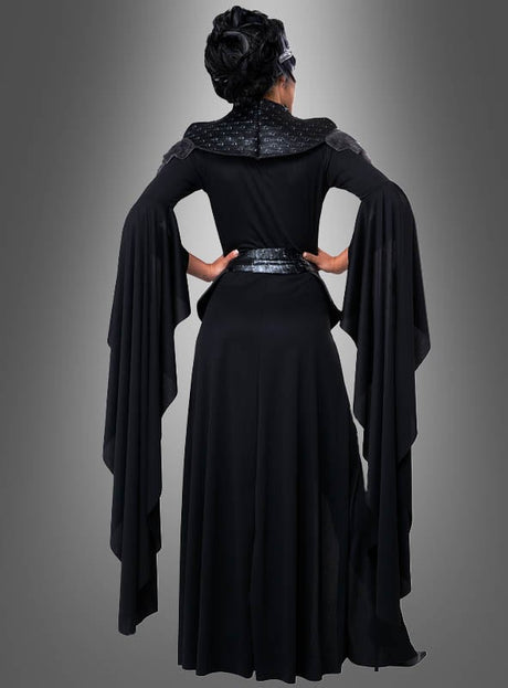 Eine Person, die das Kostüm der „Schwarzen Königin der Toten“ trägt – bestehend aus einem langen schwarzen Kleid mit dramatisch fließenden Ärmeln –, steht mit dem Rücken zu einem grauen Hintergrund mit Farbverlauf und strahlt dabei eine geheimnisvolle Eleganz aus.