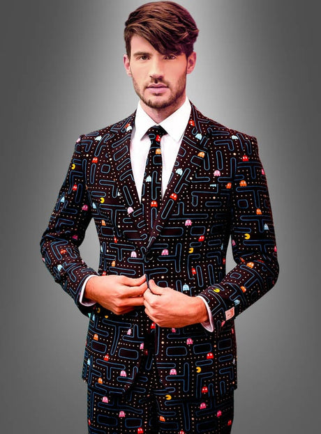 Ein Mann in einem „Deluxe Pac-Man Anzug“ von Opposuits, verziert mit einem farbenfrohen Pac-Man-Muster, steht vor einem grauen Hintergrund mit Farbverlauf, blickt in die Kamera und zieht dabei seine Jacke zurecht – ein ideales Outfit für jeden Arcade-Zocker.
